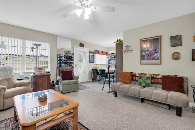 carpeted living room featuring ceiling fan and a textured ceiling