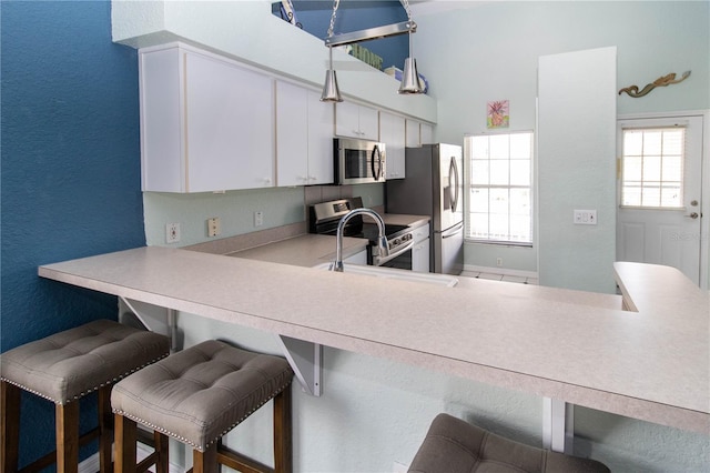 kitchen featuring a breakfast bar, white cabinetry, sink, and stainless steel appliances