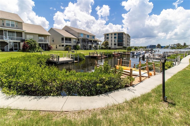 view of home's community featuring a water view, a lawn, and a boat dock