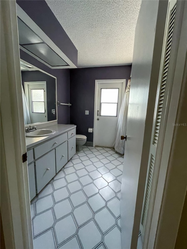 bathroom with vanity, a textured ceiling, and toilet