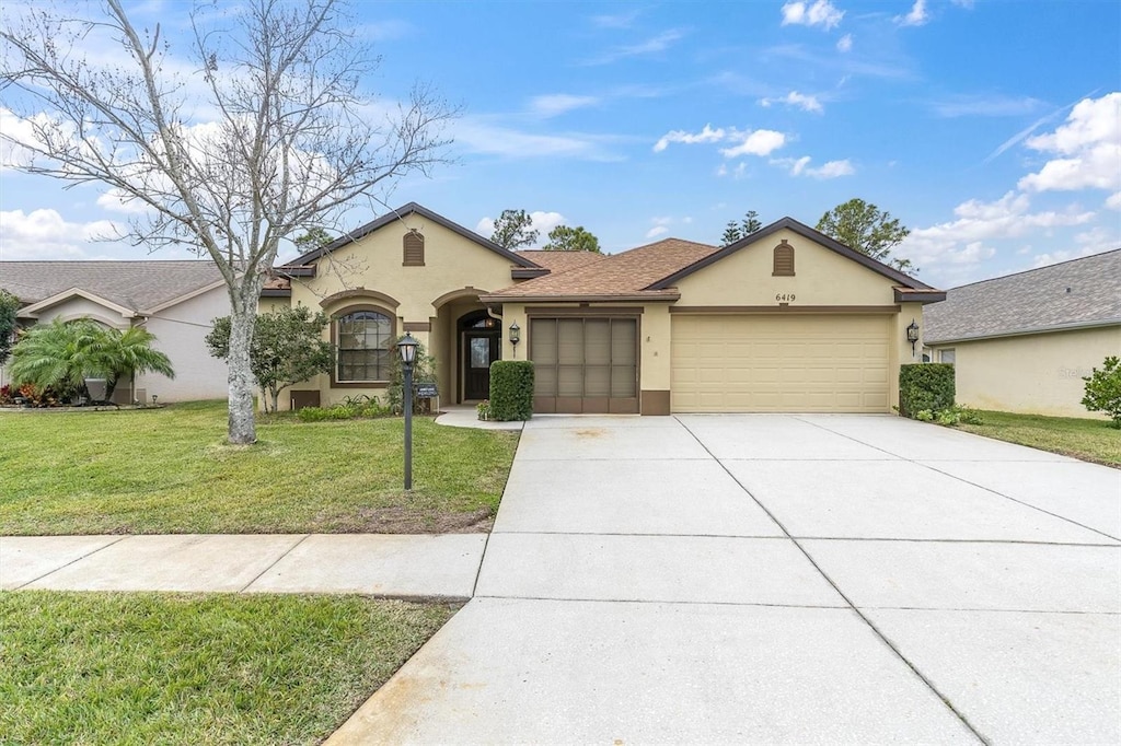 view of front of property featuring a garage, driveway, stucco siding, roof with shingles, and a front yard