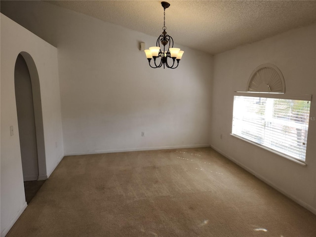 unfurnished room featuring an inviting chandelier, carpet floors, and a textured ceiling