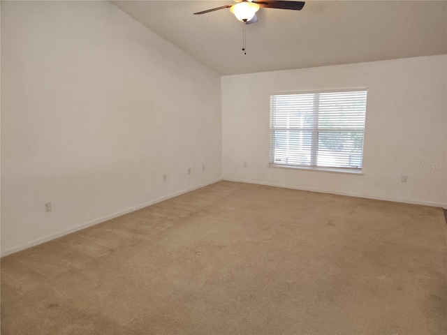 carpeted spare room featuring vaulted ceiling and ceiling fan