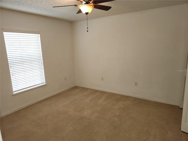 spare room with ceiling fan, light colored carpet, and a textured ceiling