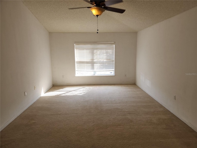 empty room with ceiling fan, light carpet, and a textured ceiling