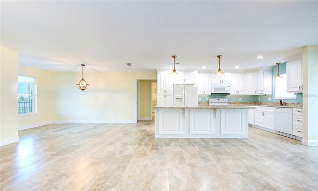 kitchen featuring white appliances, light tile patterned floors, white cabinets, a kitchen island, and light stone countertops