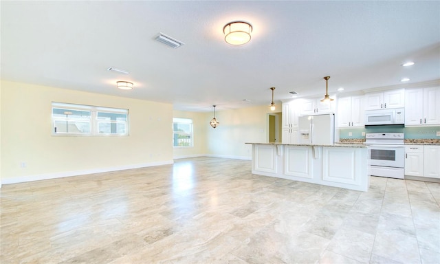 kitchen with white appliances, light tile patterned floors, white cabinets, light stone countertops, and hanging light fixtures