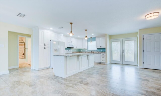 kitchen featuring white cabinetry, white appliances, light tile patterned floors, light stone counters, and a kitchen island