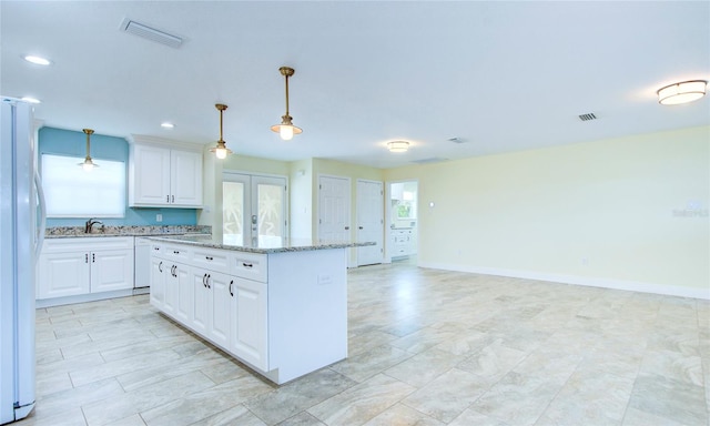 kitchen with light tile patterned flooring, white cabinetry, light stone counters, and white refrigerator