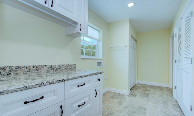 kitchen featuring white cabinetry, light tile patterned floors, and light stone counters