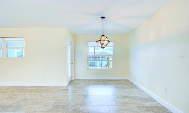 unfurnished room featuring a notable chandelier, a wealth of natural light, and light tile patterned floors