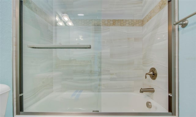 bathroom featuring shower / bath combination with glass door and toilet