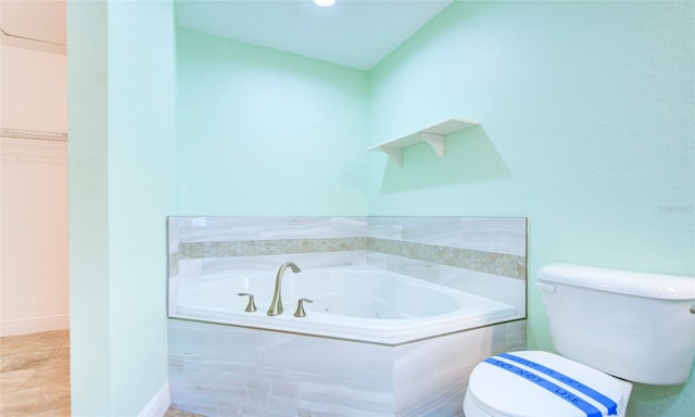 bathroom featuring tiled tub, tile patterned flooring, and toilet