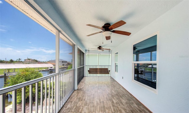 unfurnished sunroom with a water view and ceiling fan