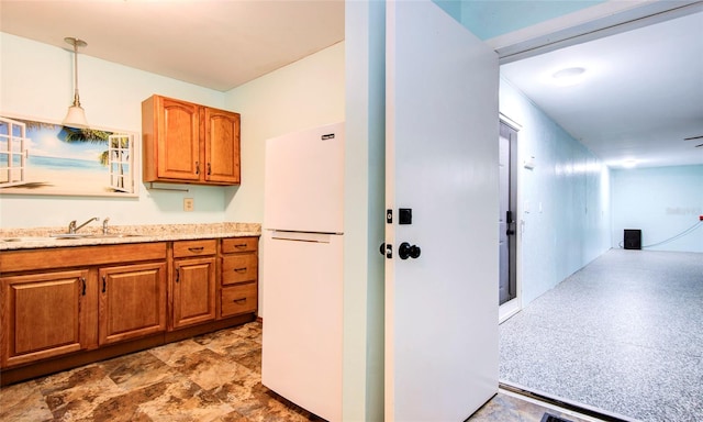 kitchen with white fridge, decorative light fixtures, sink, light stone counters, and light tile patterned floors