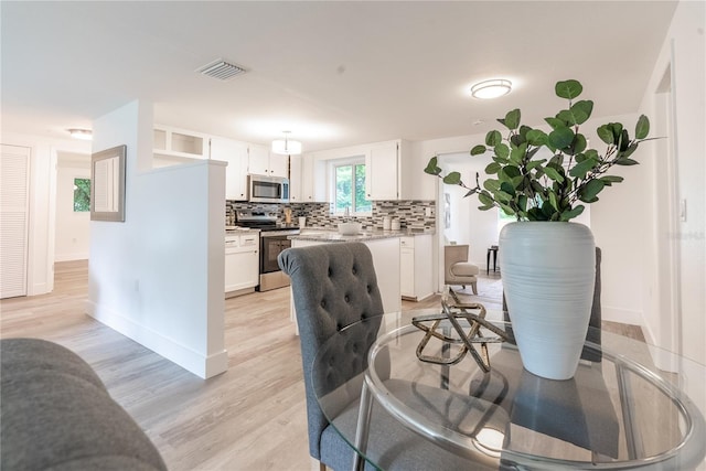 dining area featuring light wood-type flooring, visible vents, and baseboards