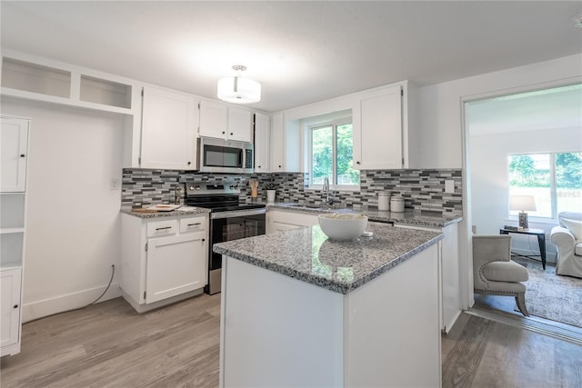 kitchen with white cabinetry, light wood-type flooring, light stone countertops, appliances with stainless steel finishes, and decorative backsplash