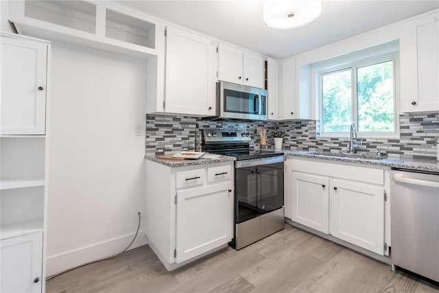 kitchen featuring white cabinets, backsplash, appliances with stainless steel finishes, and light wood-type flooring