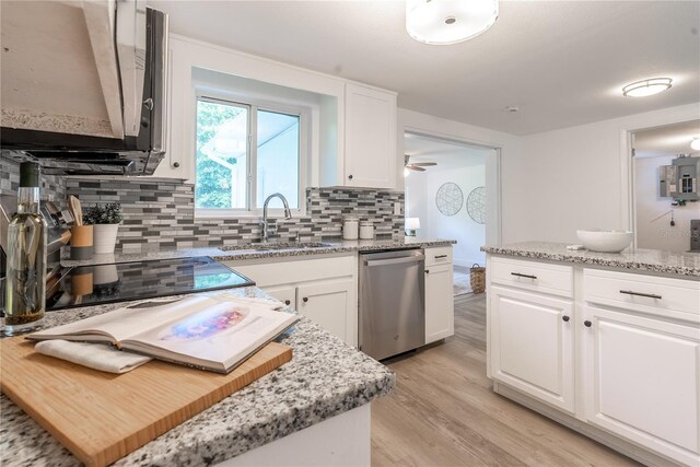 kitchen with stainless steel dishwasher, white cabinetry, light hardwood / wood-style flooring, and backsplash