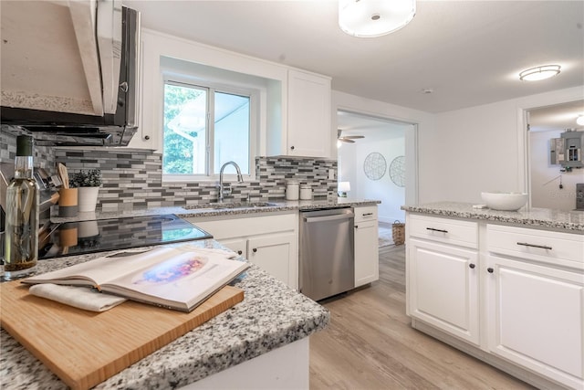 kitchen featuring light wood finished floors, a kitchen island, stainless steel dishwasher, white cabinetry, and a sink