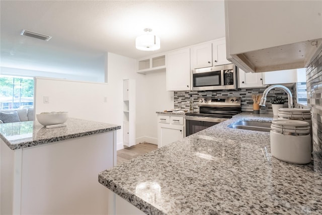 kitchen featuring stainless steel appliances, white cabinetry, a sink, and visible vents