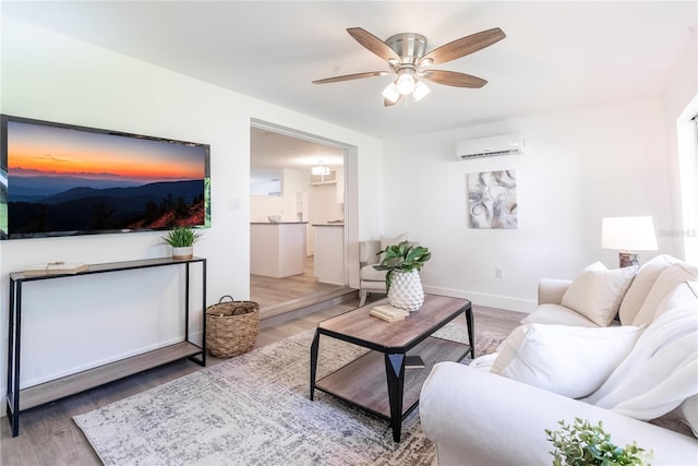 living area featuring ceiling fan, baseboards, wood finished floors, and a wall mounted AC