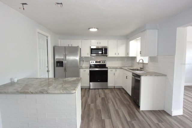 kitchen with appliances with stainless steel finishes, sink, wood-type flooring, and white cabinets