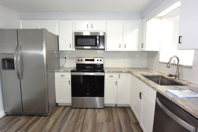 kitchen with appliances with stainless steel finishes, white cabinetry, tasteful backsplash, sink, and dark hardwood / wood-style flooring