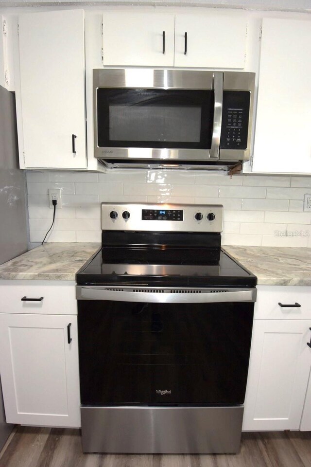 kitchen featuring stainless steel appliances, dark wood-type flooring, white cabinetry, and tasteful backsplash