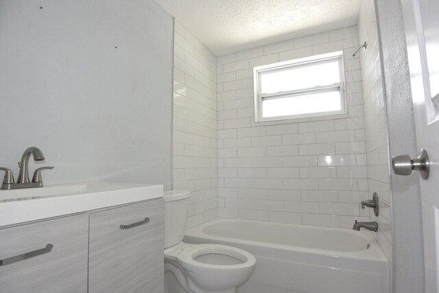 full bathroom with a textured ceiling, vanity, tiled shower / bath, and toilet