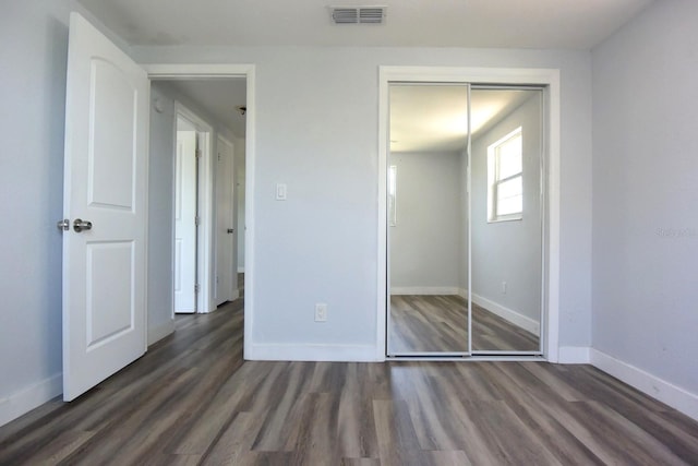 unfurnished bedroom featuring a closet and dark hardwood / wood-style flooring