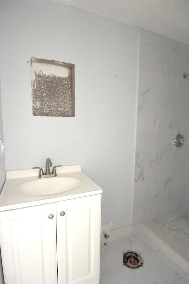 bathroom with a tile shower and vanity