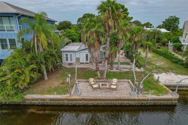 rear view of house with an outdoor fire pit, a patio, a water view, and an outbuilding