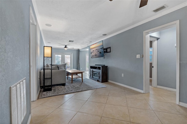 living room featuring a wood stove, ceiling fan, ornamental molding, and light tile patterned floors