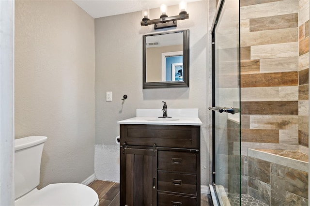 bathroom featuring a shower with door, vanity, and toilet