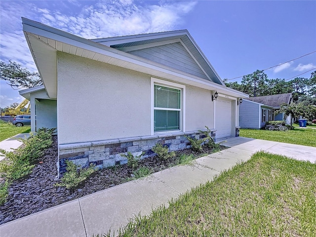 view of side of property featuring a garage and a lawn