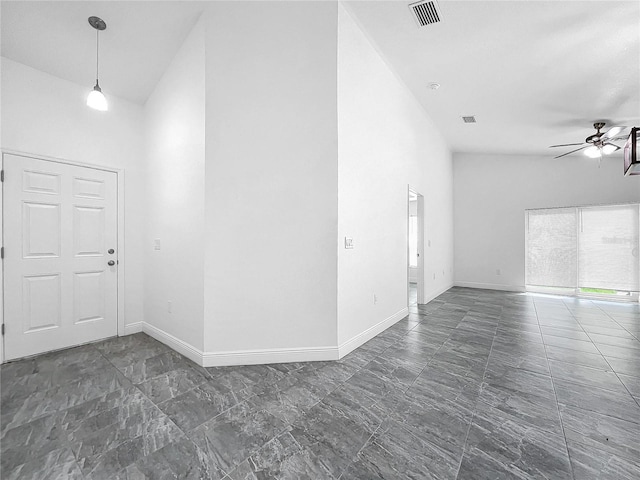 tiled spare room featuring ceiling fan and a towering ceiling