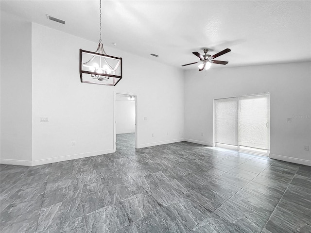 spare room with ceiling fan with notable chandelier, lofted ceiling, and dark tile patterned flooring