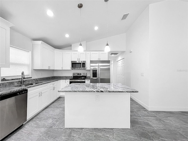 kitchen with a center island, tile patterned floors, hanging light fixtures, appliances with stainless steel finishes, and vaulted ceiling