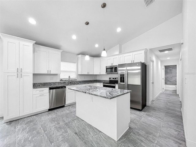 kitchen with light tile patterned flooring, white cabinetry, a kitchen island, appliances with stainless steel finishes, and vaulted ceiling