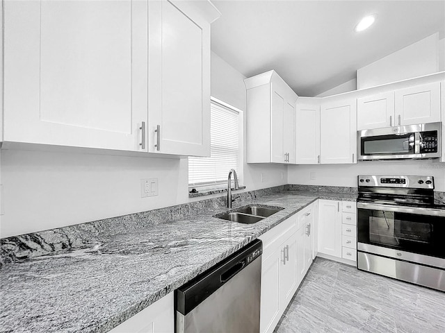 kitchen with stainless steel appliances, sink, light stone countertops, lofted ceiling, and white cabinetry