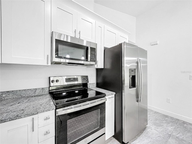 kitchen with appliances with stainless steel finishes, white cabinetry, light tile patterned floors, and light stone countertops