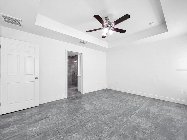 tiled spare room with ceiling fan and a raised ceiling