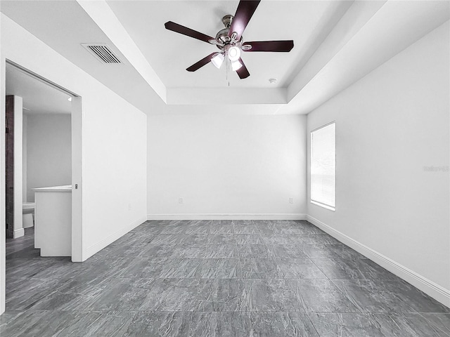 tiled spare room with a raised ceiling and ceiling fan