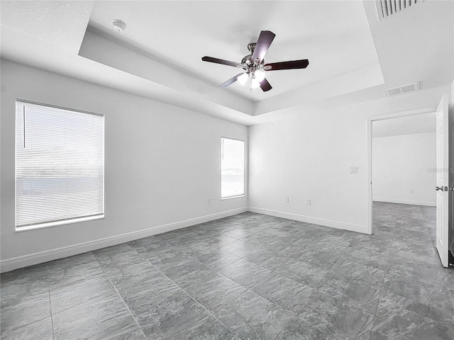 unfurnished room featuring ceiling fan, a raised ceiling, and tile patterned floors