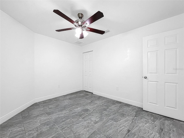 empty room with dark tile patterned floors and ceiling fan