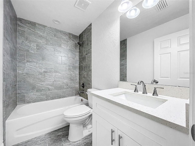 full bathroom with vanity, tile patterned floors, tiled shower / bath, toilet, and a textured ceiling