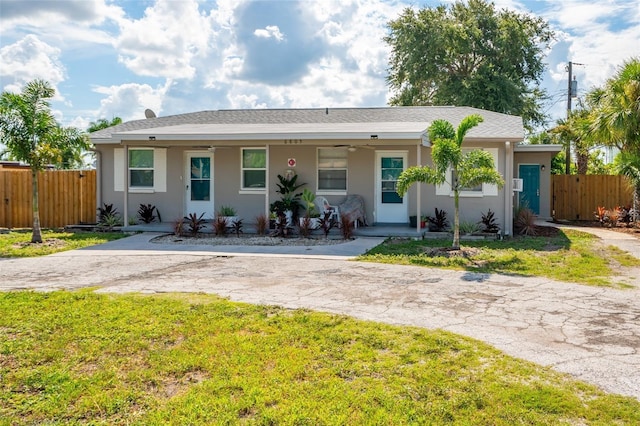 ranch-style home featuring covered porch and a front lawn