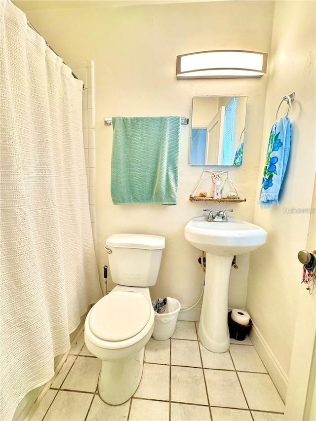 bathroom with walk in shower, sink, tile patterned floors, and toilet