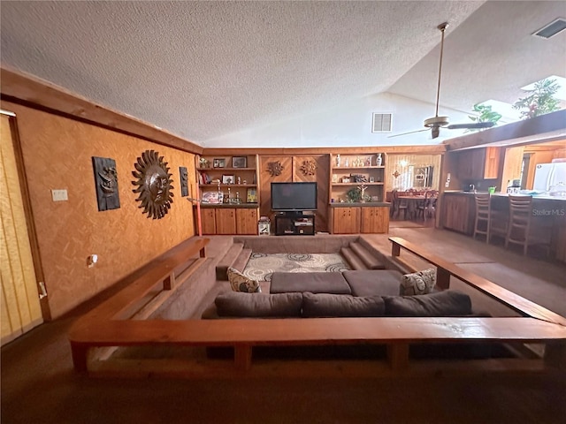 living room featuring ceiling fan, lofted ceiling, a textured ceiling, and built in shelves